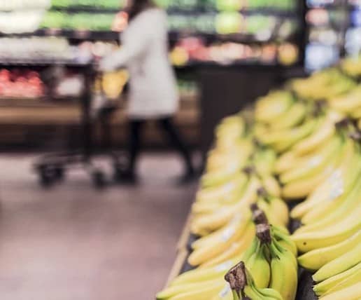 A woman in the background saving money at the grocery store.