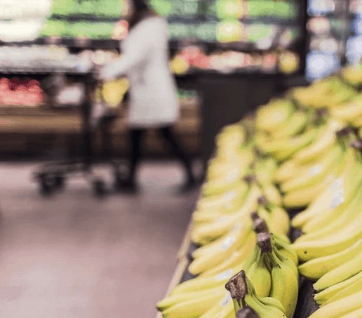 A woman in the background saving money at the grocery store.